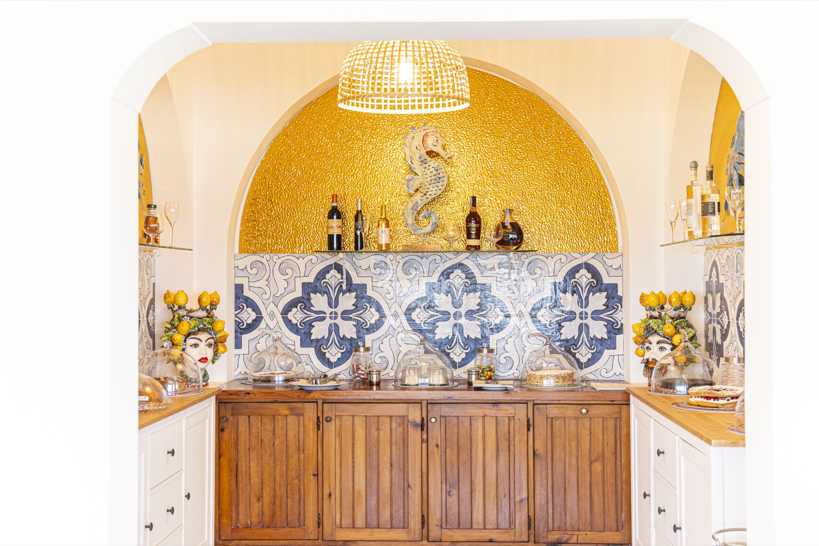 L'angolo bar con l'arco dorato, le maioliche blu e le teste di moro con i limoni